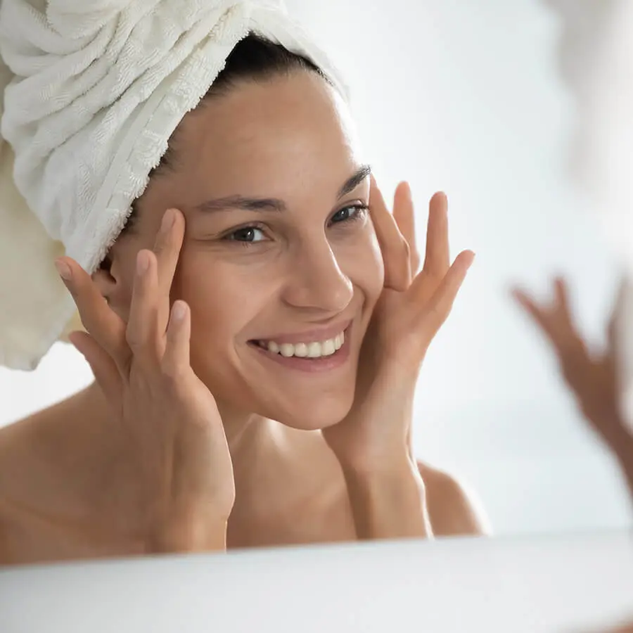 woman happily reviewing her face after a shower